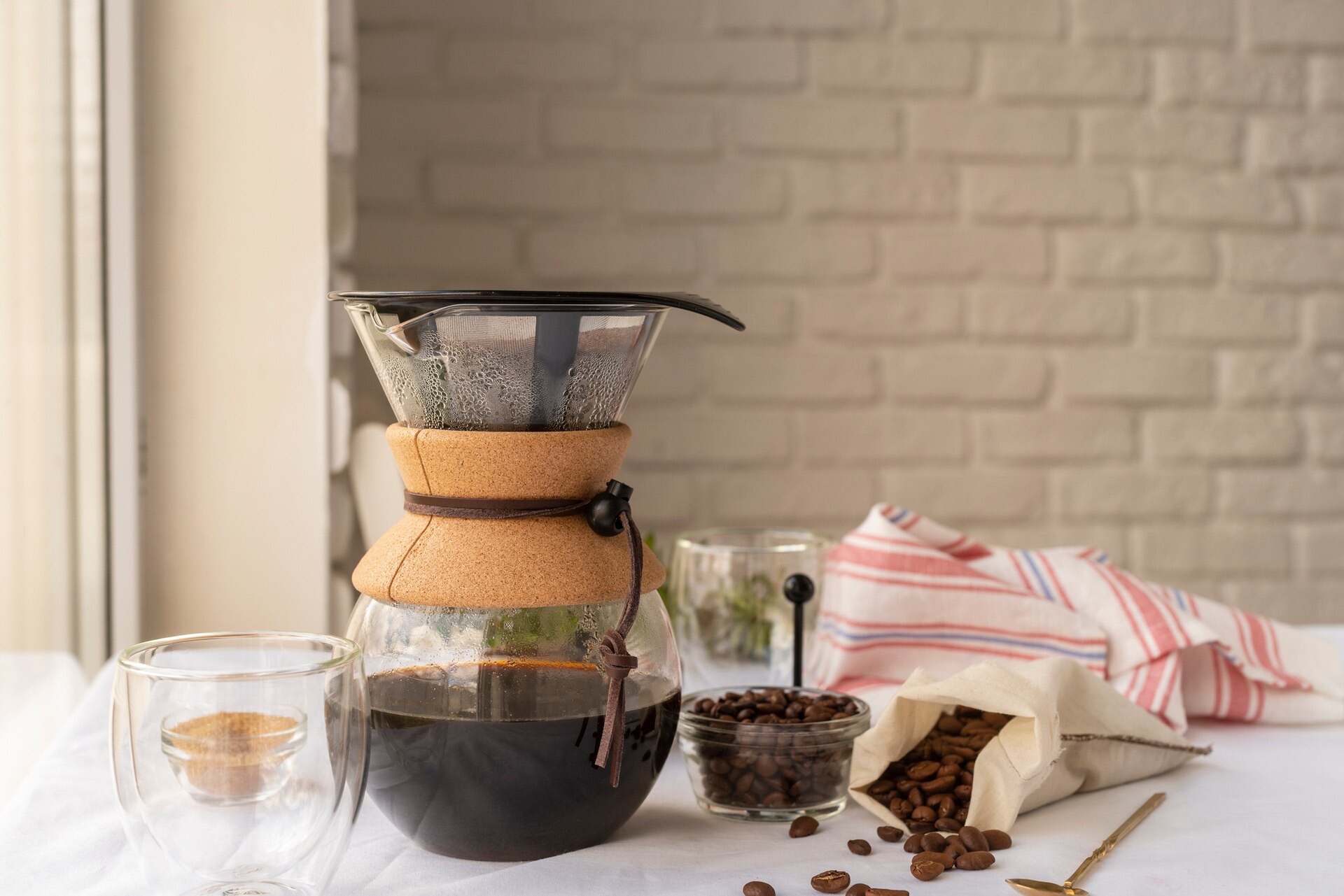 Glaskaraff med nybryggt kaffe och kaffebönor på ett köksbord